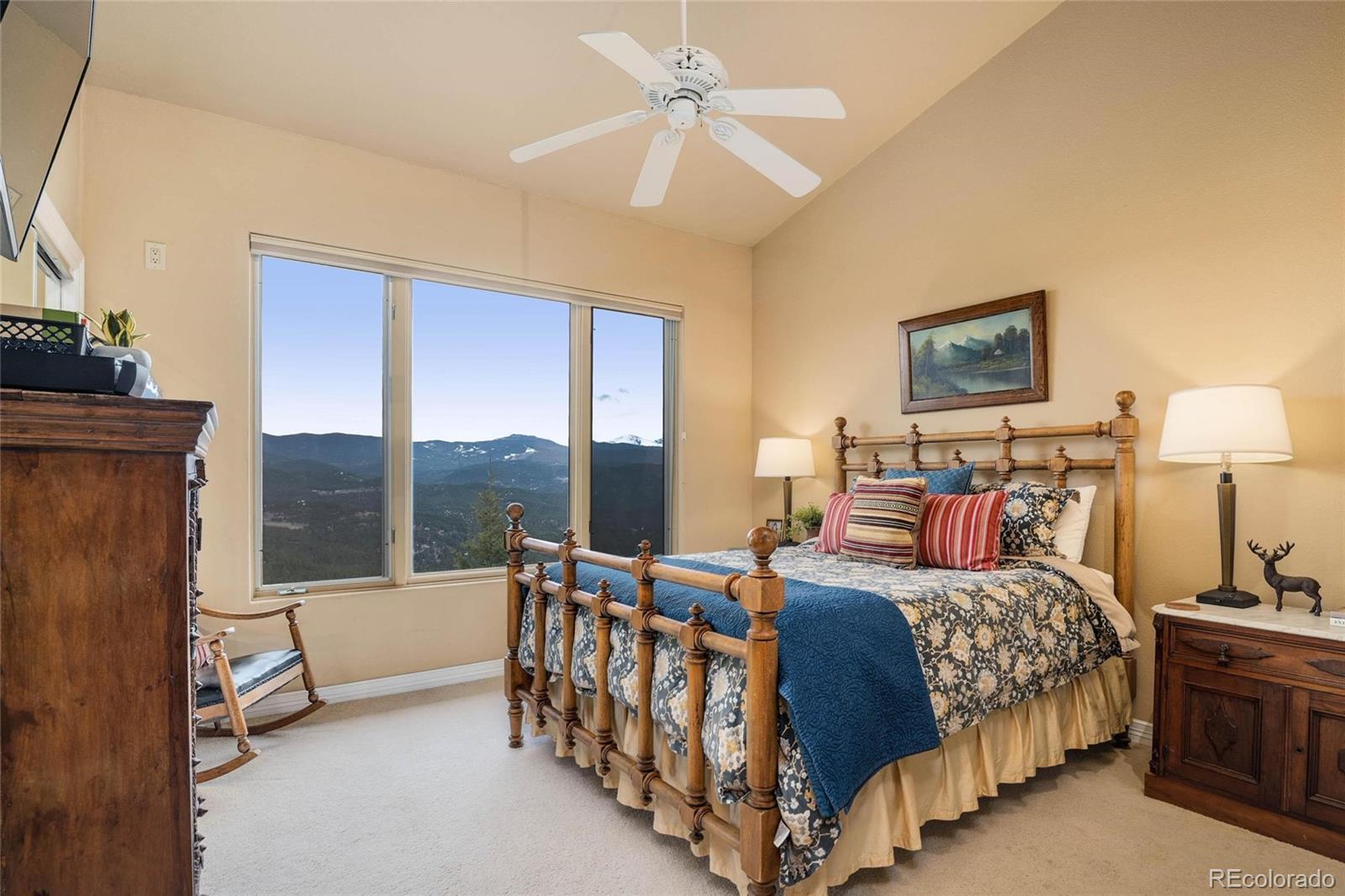 25580 Sunset Lane Evergreen, CO 80439 - Photo 22 of 40 a bedroom with a bed and a chandelier