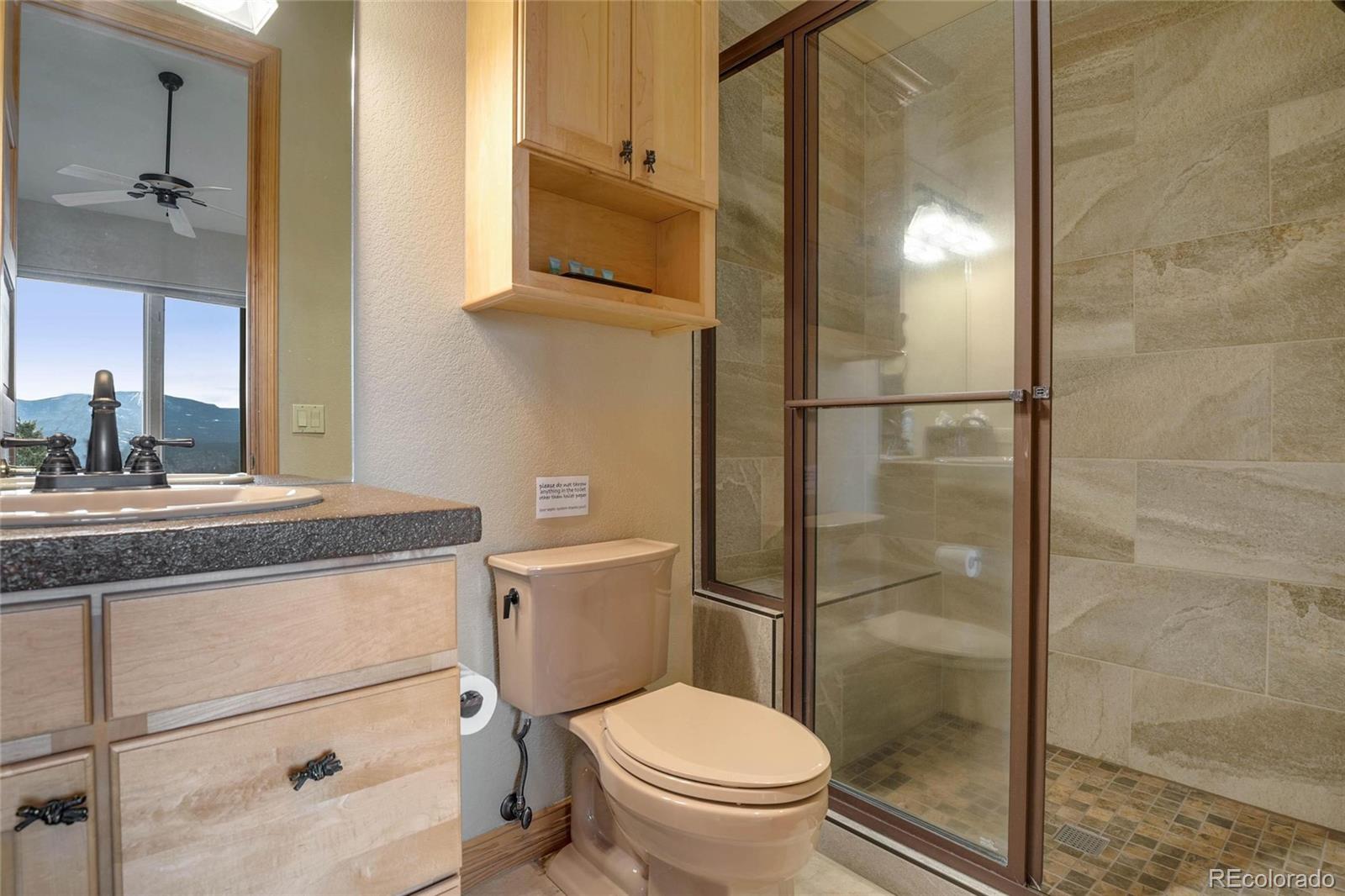 25580 Sunset Lane Evergreen, CO 80439 - Photo 23 of 40 a bathroom with a granite countertop toilet sink and shower