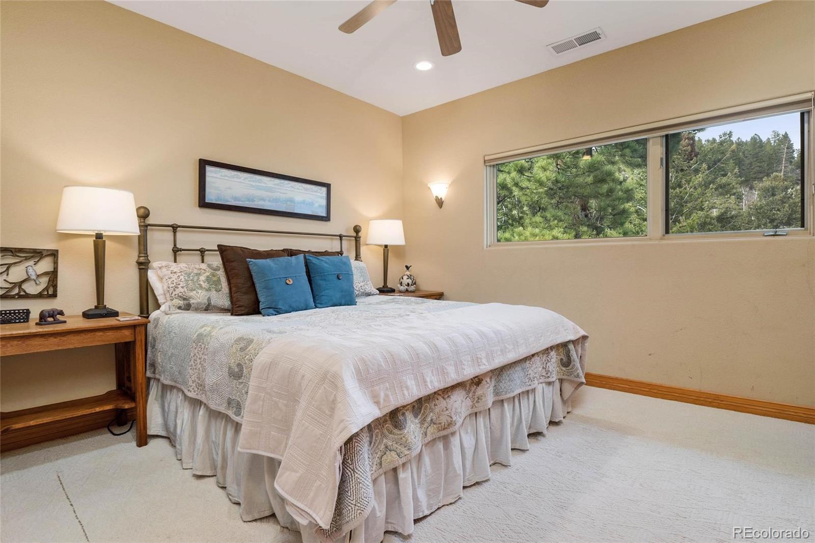 25580 Sunset Lane Evergreen, CO 80439 - Photo 28 of 40 a bedroom with a bed and a lamp on table