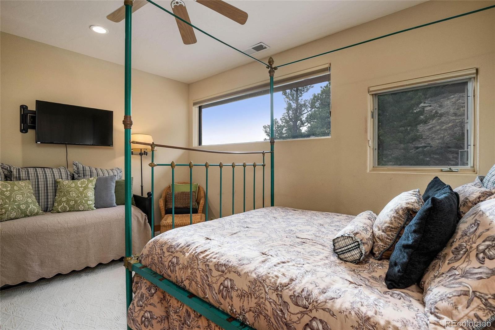 25580 Sunset Lane Evergreen, CO 80439 - Photo 30 of 40 a bedroom with a bed a couch and a flat screen tv