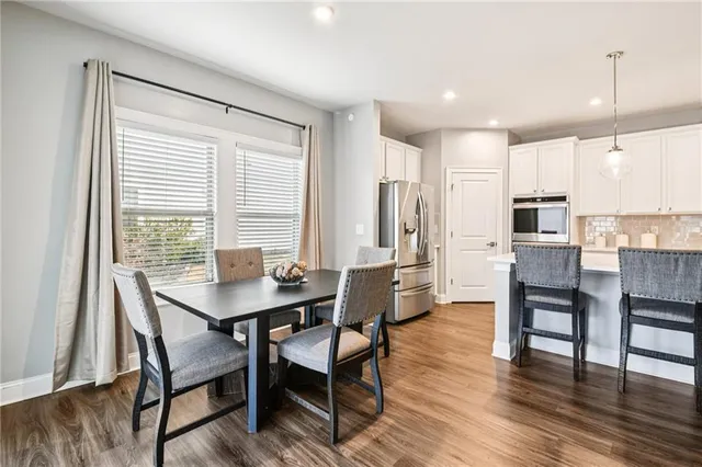 a kitchen with stainless steel appliances granite countertop a dining table chairs stove refrigerator and cabinets