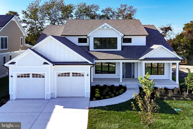 a view of a white house with a yard plants and large tree