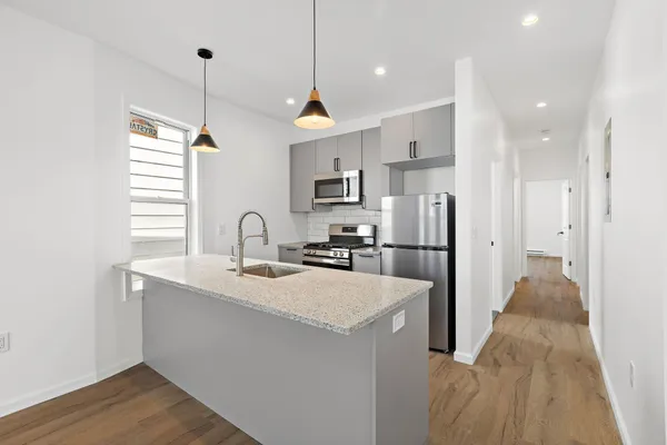 a large kitchen with stainless steel appliances granite countertop a refrigerator a sink dishwasher a oven with white cabinets and wooden floor