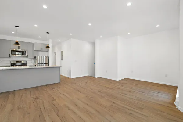 a large white kitchen with kitchen island a sink wooden floor and a counter top space