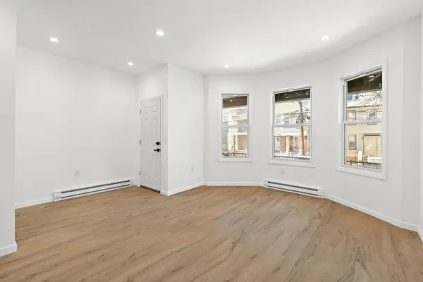a view of an empty room with wooden floor and windows