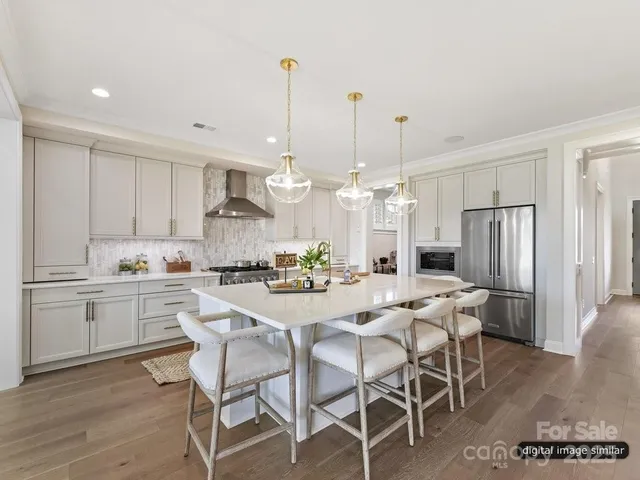 a kitchen with stainless steel appliances kitchen island granite countertop a dining table chairs and white cabinets