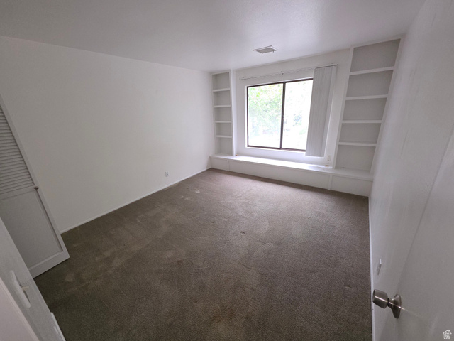 6852 Countrywoods Circle, Unit 5D Midvale, UT 84047 - Photo 22 of 50 Room featuring a large window, built-in shelving, a window bench with full storage, and carpeted flooring