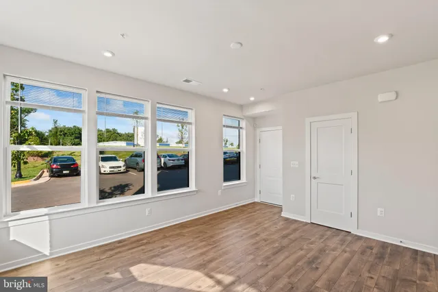 a view of an empty room with window and wooden floor