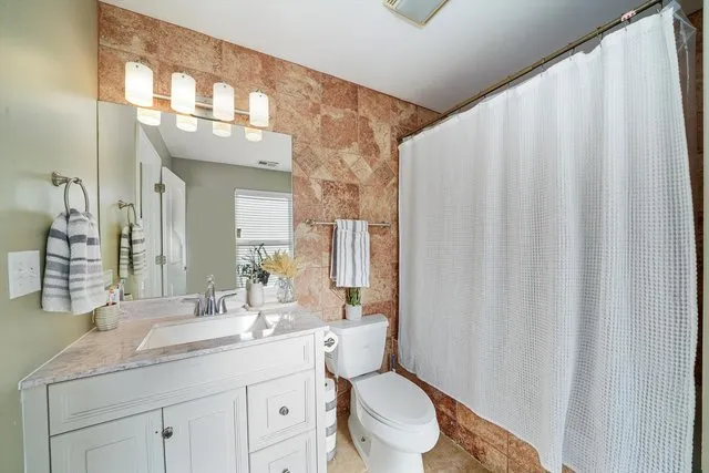 a bathroom with a granite countertop sink a toilet and a mirror
