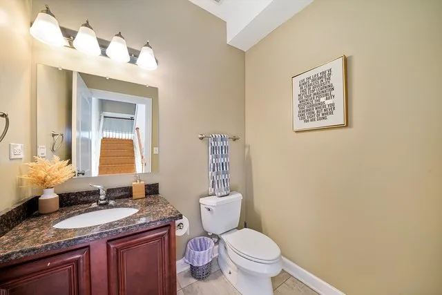 a bathroom with a granite countertop toilet sink and mirror