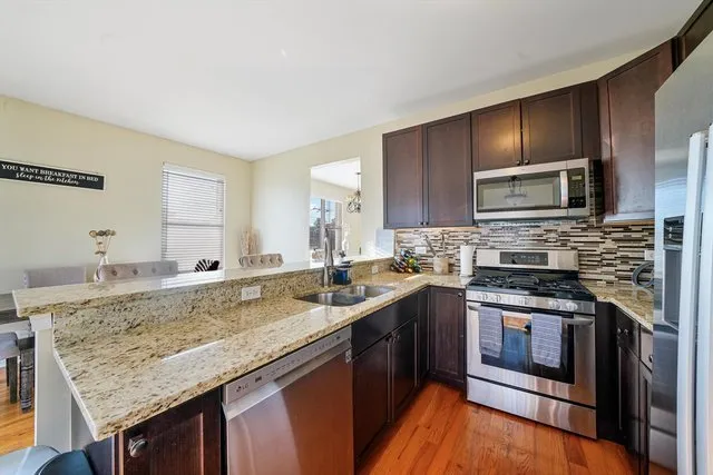 a kitchen with stainless steel appliances granite countertop a stove a sink and a microwave