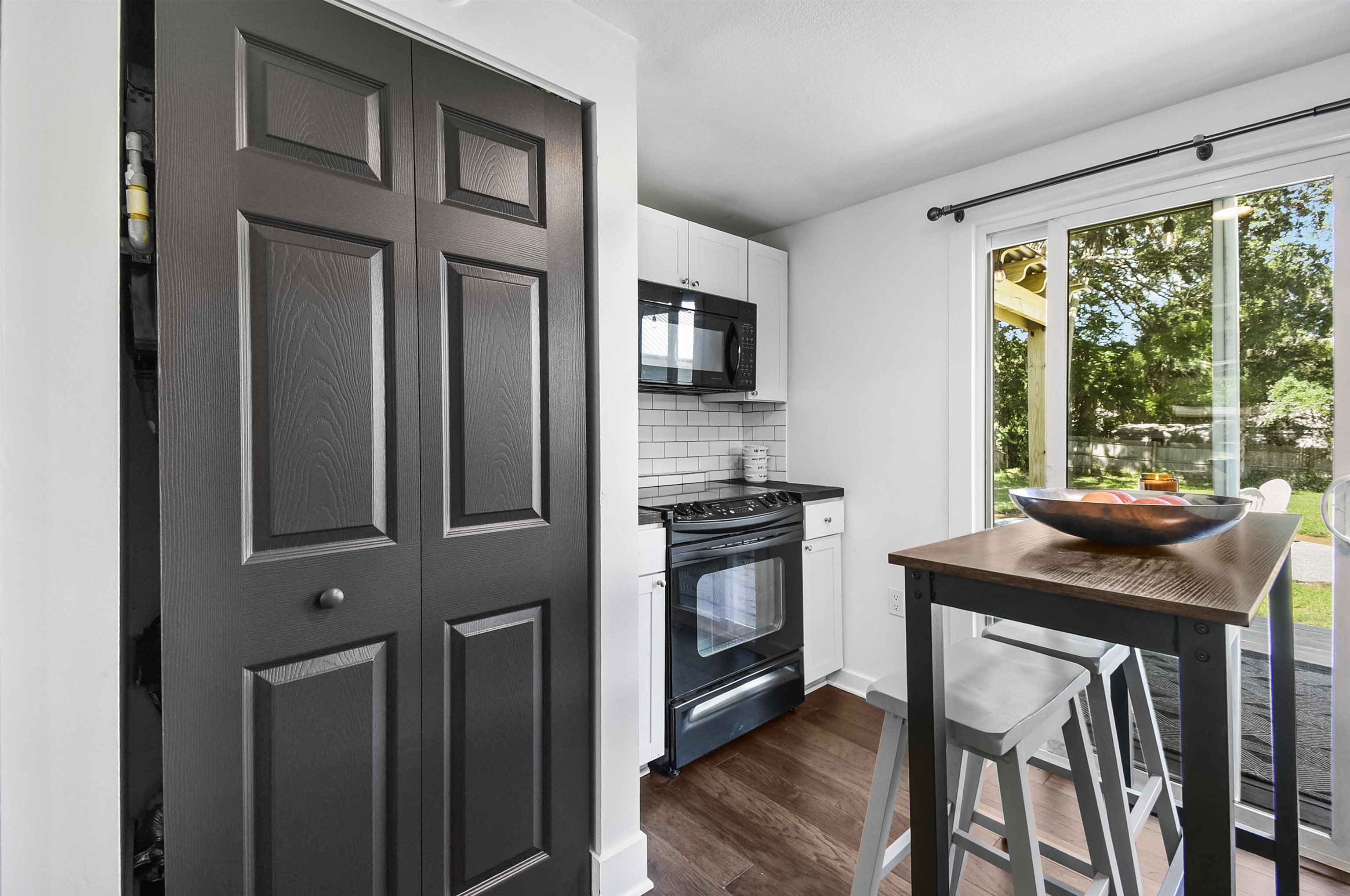 207 Spring Street St. Augustine, FL 32084 - Photo 20 of 32 a kitchen with stainless steel appliances granite countertop a stove a refrigerator a microwave oven with a dining table and chairs