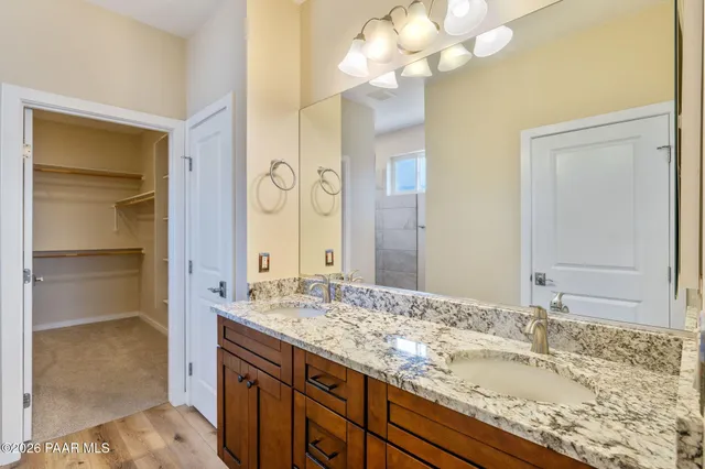 a bathroom with a granite countertop double vanity sink and a mirror