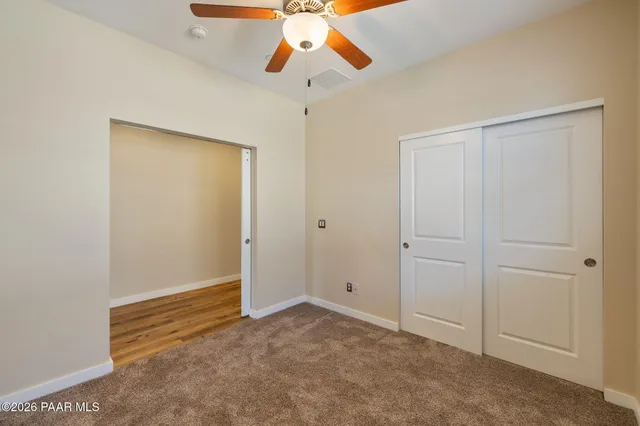 an empty room with closet and chandelier fan