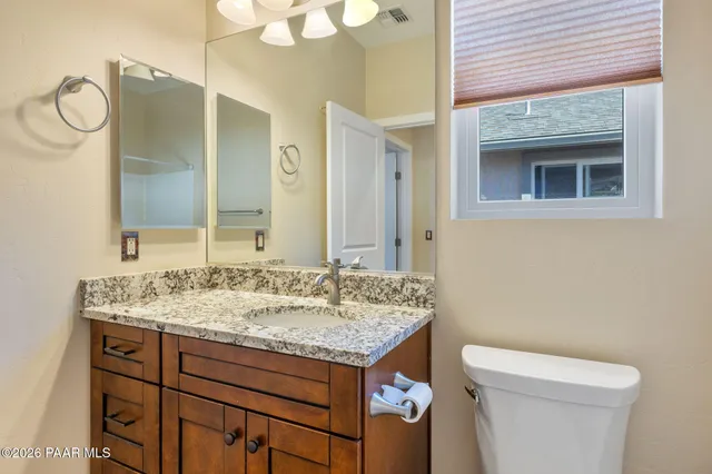 a bathroom with a granite countertop sink a toilet and a mirror