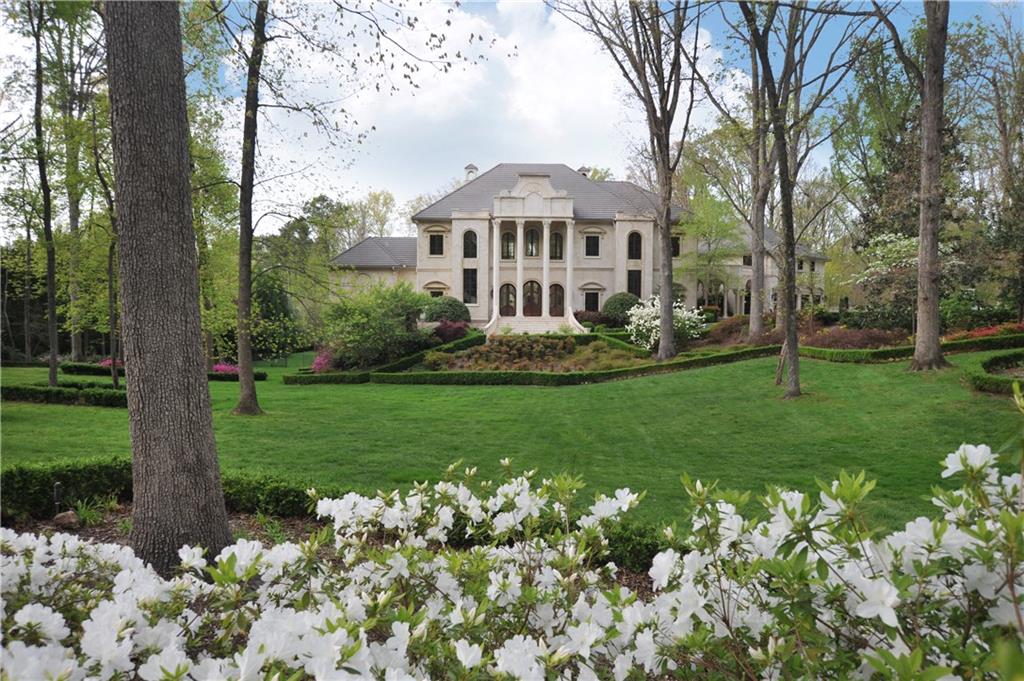 a front view of a house with a garden and trees