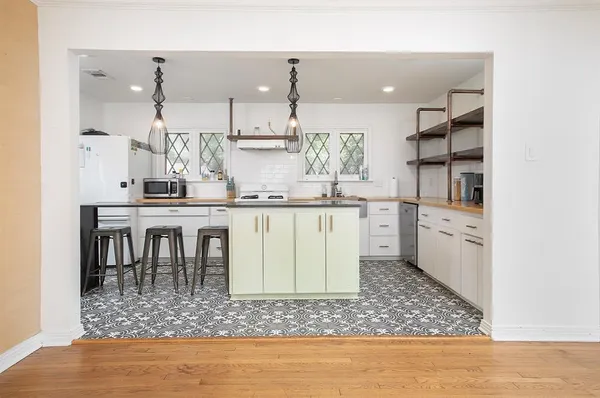 a living room with stainless steel appliances kitchen island granite countertop a refrigerator and a wooden floor