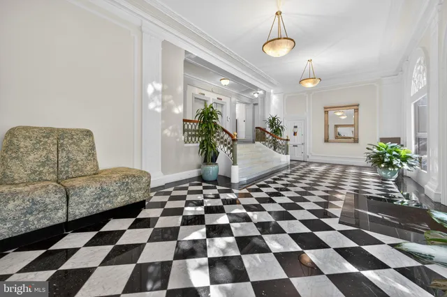 a living room with a black white checkered floor with couches chair and a coffee table