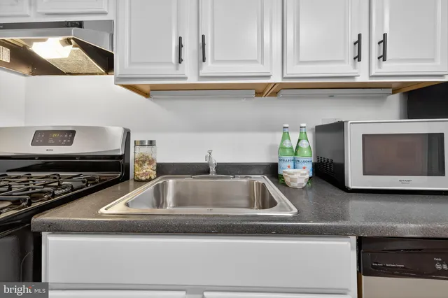 a kitchen with granite countertop a sink stainless steel appliances and cabinets