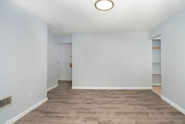 a view of an empty room with wooden floor and fan