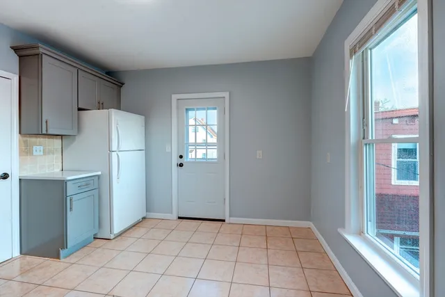 a kitchen with white cabinets and refrigerator