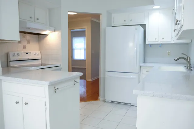 a kitchen with a refrigerator a stove and white cabinets