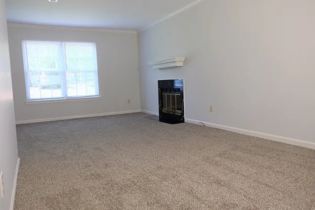 a view of an empty room with a window and a fireplace
