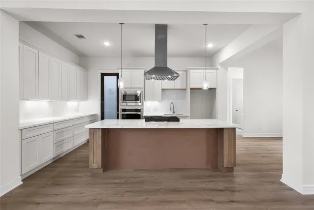 a large kitchen with stainless steel appliances a large counter top a stove and a refrigerator