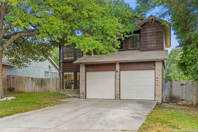 front view of a house with a yard and an trees