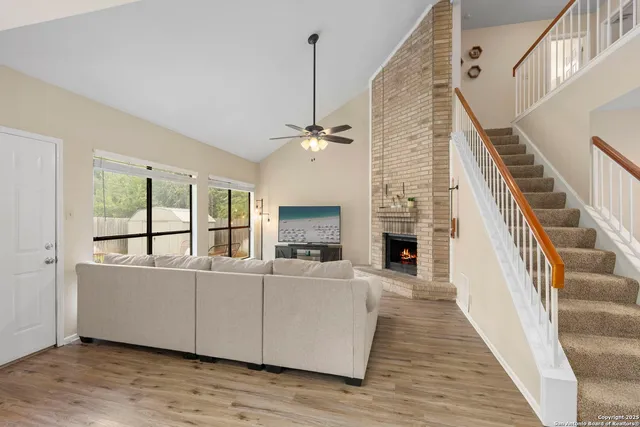 a view of a livingroom with furniture wooden floor fireplace and staircase