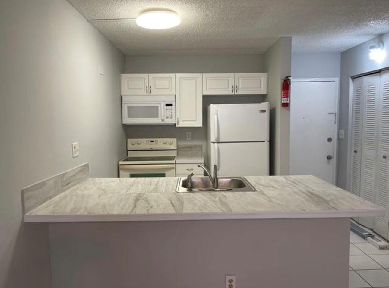 2701 Riverside Drive, Unit 107B Coral Springs, FL 33065 - Photo 1 of 13 a kitchen with granite countertop a refrigerator and a sink