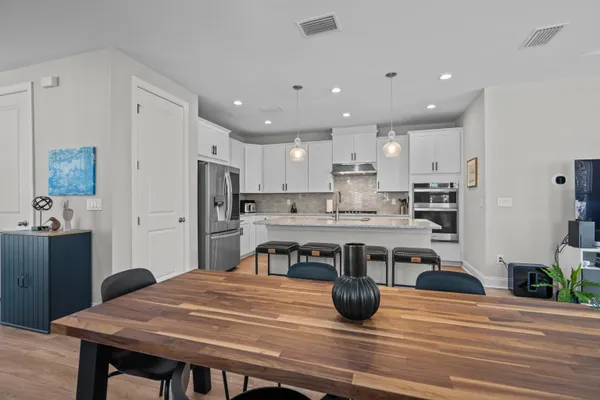 a kitchen with stainless steel appliances wooden floor dining table and chairs