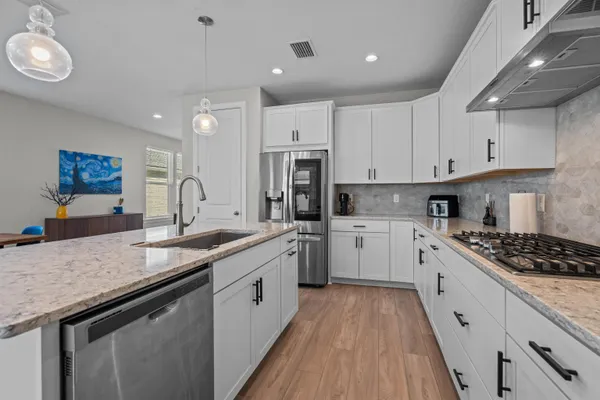 a kitchen with granite countertop stainless steel appliances a sink stove top oven and cabinets