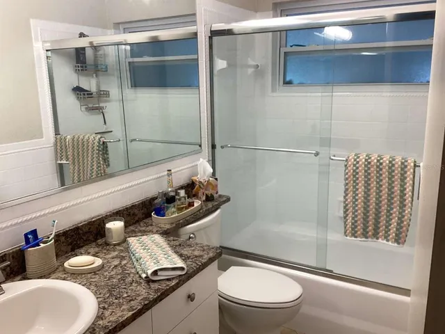 a bathroom with a granite countertop sink mirror vanity and toilet