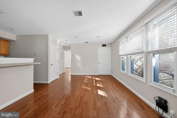 a view of an empty room with wooden floor and a window