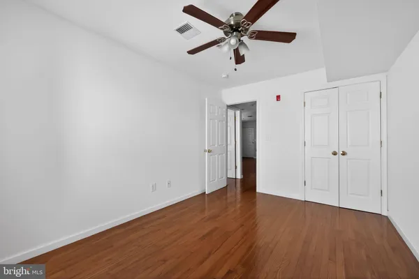 an empty room with wooden floor ceiling fan and windows