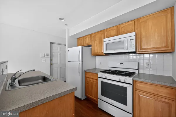 a kitchen with granite countertop a sink stove and microwave
