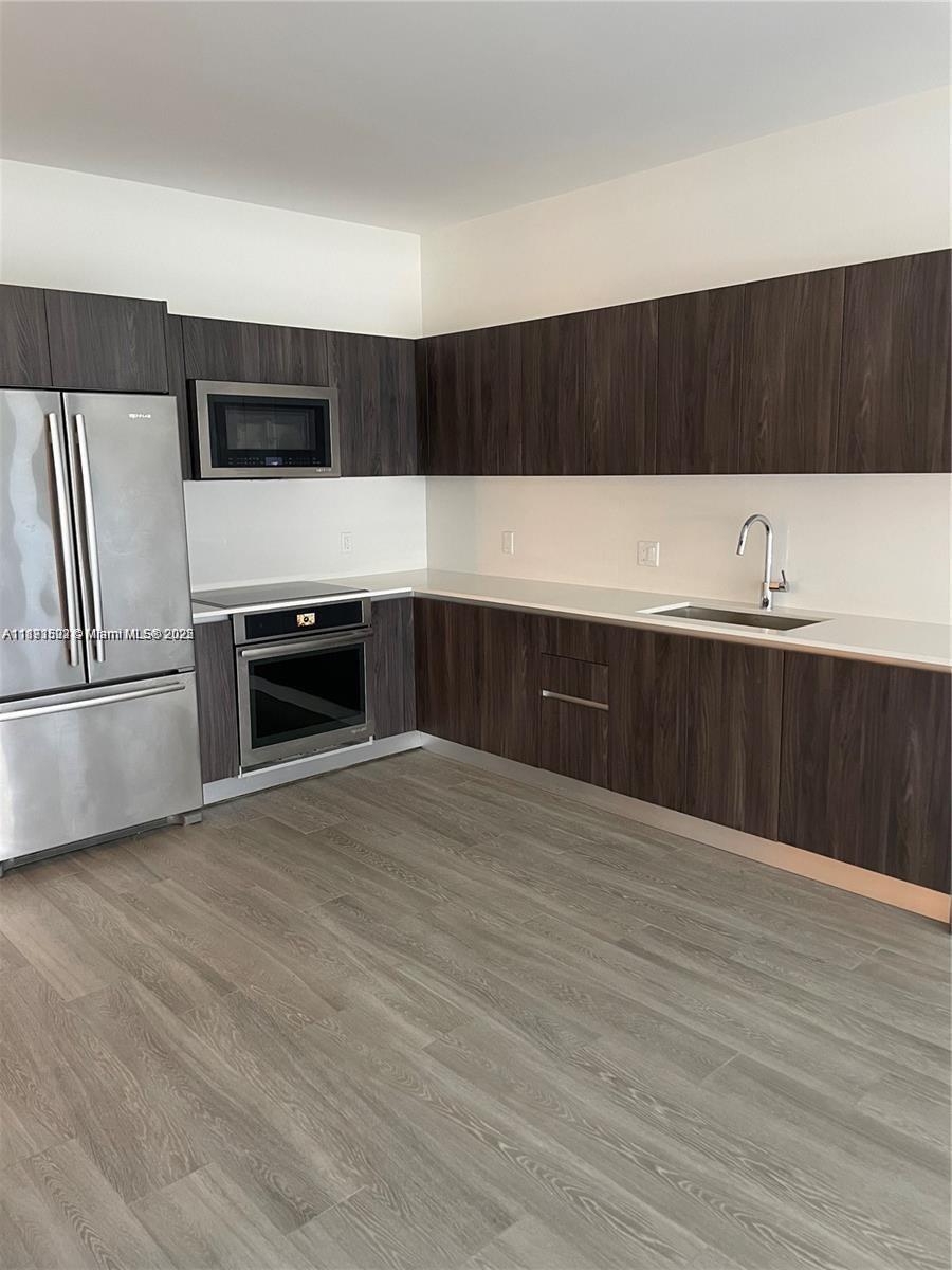 2960 Northeast 207th Street, Unit 1106 Aventura, FL 33180 - Photo 20 of 31 a kitchen with wooden cabinets and stainless steel appliances