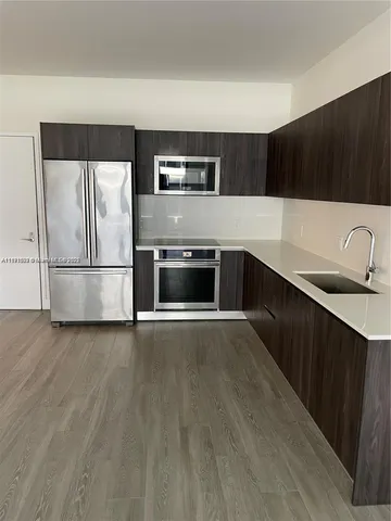 a view of a multi story residential apartment building with a yard and plants