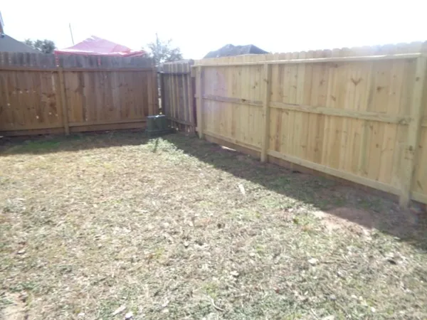 a view of backyard with small cabin and wooden fence