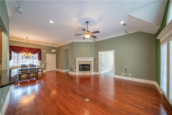 an empty room with wooden floor and chandelier fan