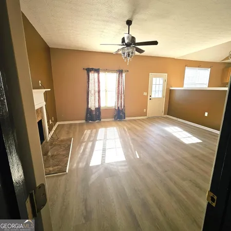 a view of an empty room with window and wooden floor
