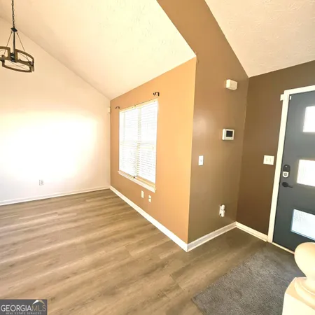 a view of an empty room with window and wooden floor