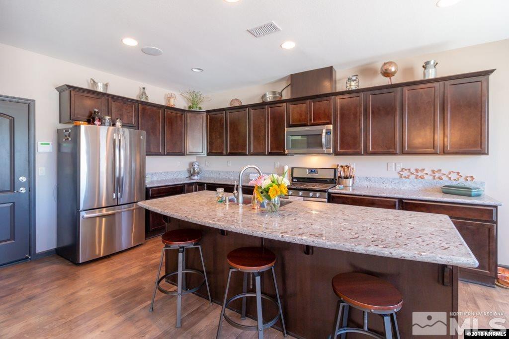 9635 Caitlin Court Reno, NV 89521 - Photo 6 of 23 a kitchen with granite countertop a stove a sink a refrigerator and wooden cabinets