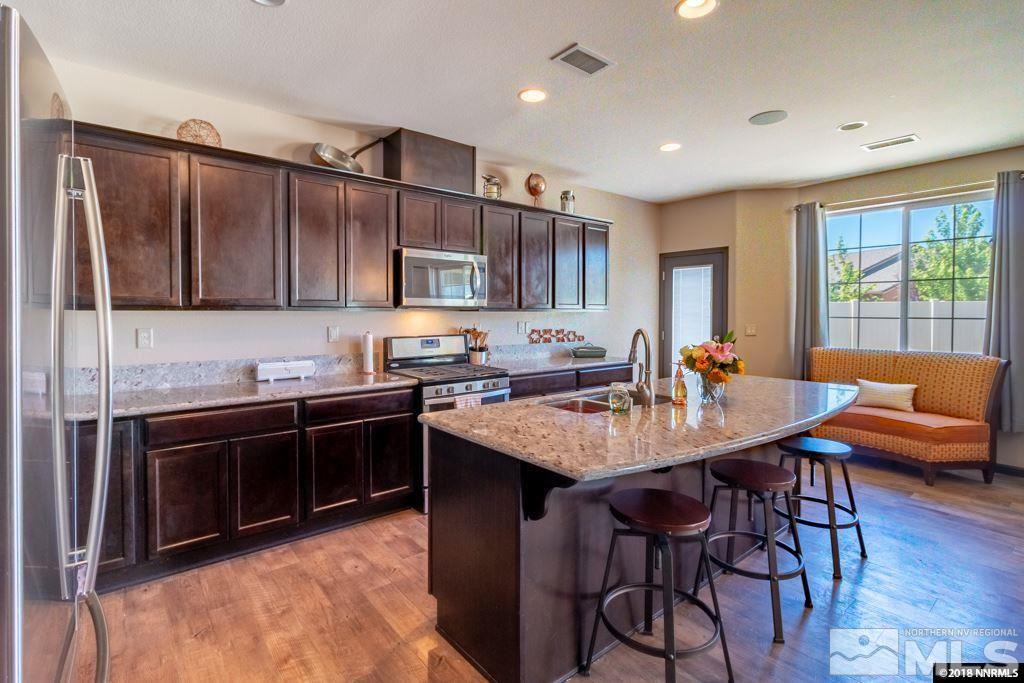 9635 Caitlin Court Reno, NV 89521 - Photo 7 of 23 a kitchen with stainless steel appliances granite countertop a stove a sink a microwave a dining table and chairs