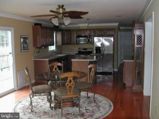 15 West Torquay Road Ocean City, MD 21842 - Photo 3 of 6 a dining room with wooden floor a chandelier a wooden table and chairs