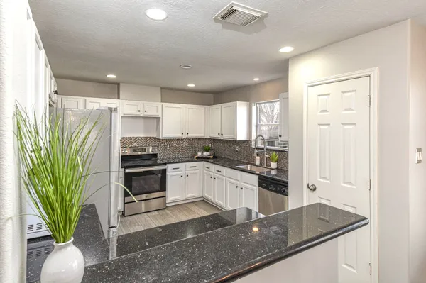 a kitchen with granite countertop white cabinets and white appliances