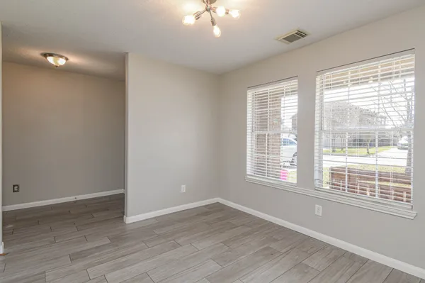 a view of an empty room with a window and wooden floor