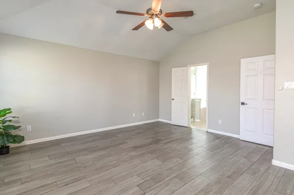 an empty room with wooden floor closet and windows