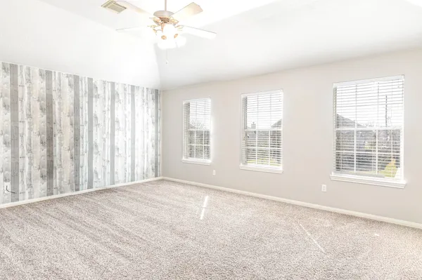 a view of an empty room with a window and hardwood floor